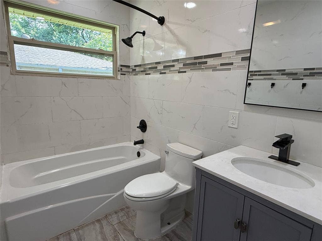 13430 Challaburton Drive, Farmers Branch, TX 75234 Bathroom featuring a white bathtub, toilet, and a vanity with a white countertop and gray cabinetry