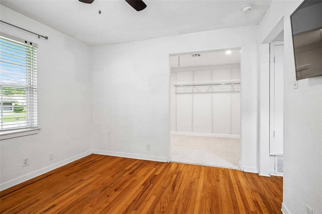 13430 Challaburton Drive, Farmers Branch, TX 75234 Room featuring wood flooring, neutral wall tones, two windows with blinds, and a ceiling fan with integrated lighting