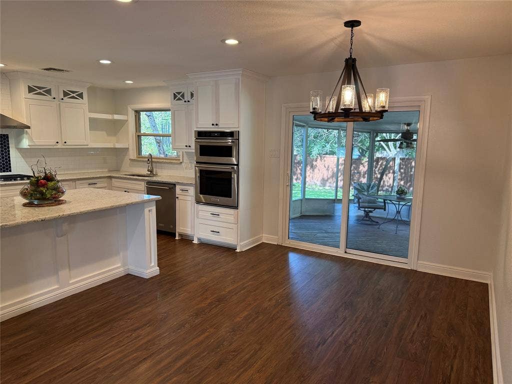 13430 Challaburton Drive, Farmers Branch, TX 75234 Kitchen featuring wood-finish flooring, white cabinetry, a granite island countertop, and built-in stainless steel appliances