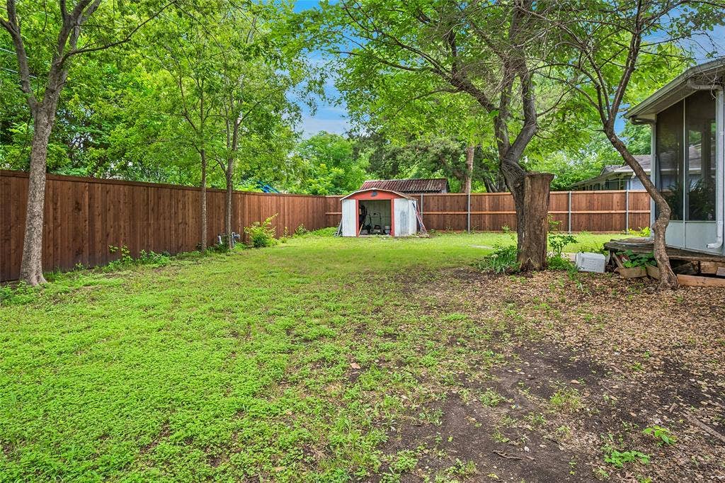 13430 Challaburton Drive, Farmers Branch, TX 75234 Expansive rear yard featuring a privacy fence, established trees, a storage shed, and a screened porch area