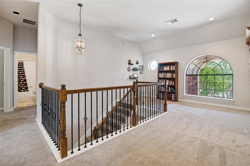 4305 Loch Haven Court, McKinney, TX 75072 Spacious landing area featuring a decorative wrought iron and wood baluster, vaulted ceilings, a large arched window with grid detailing, and recessed lighting