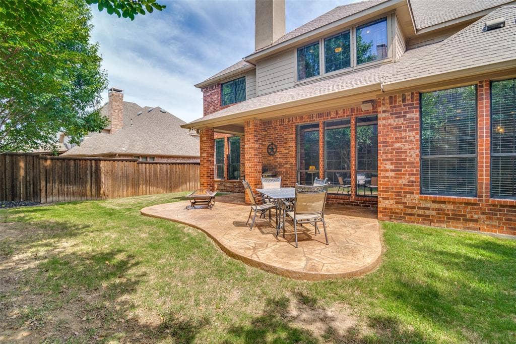4305 Loch Haven Court, McKinney, TX 75072 Expansive backyard featuring a stamped concrete patio, brick exterior, covered patio area, numerous large windows, and a privacy fence