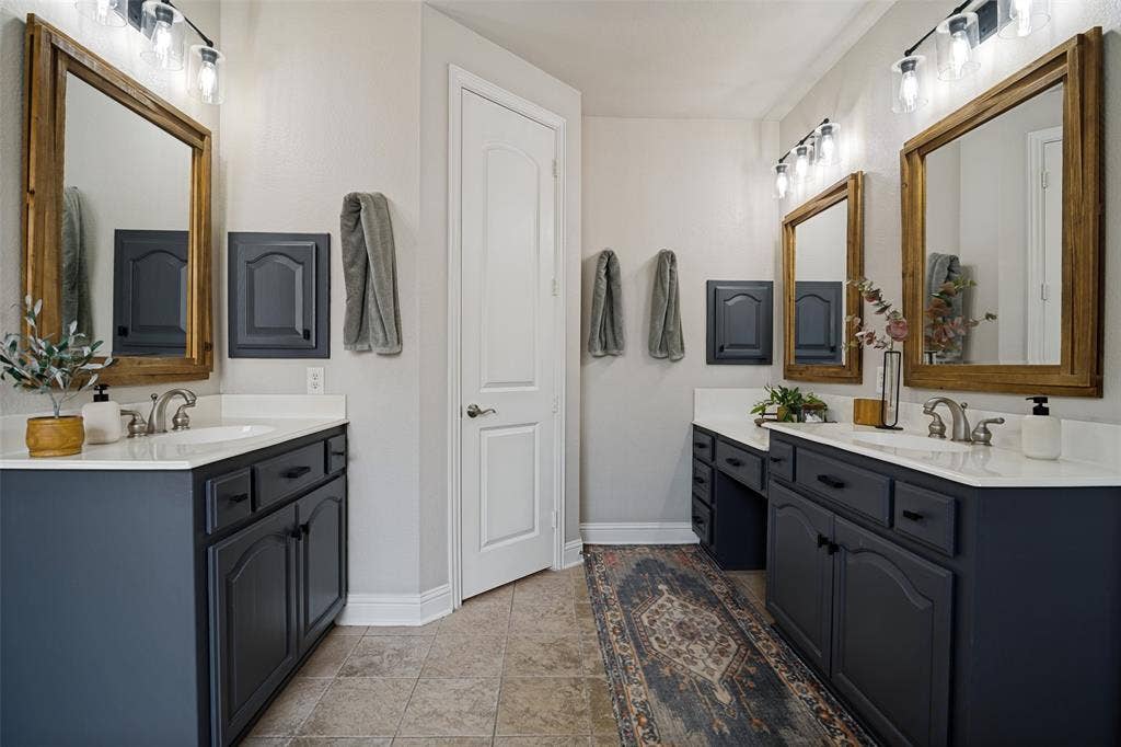 4305 Loch Haven Court, McKinney, TX 75072 Dual vanity bathroom featuring stone countertops, dark cabinetry, and individual framed mirrors with overhead lighting