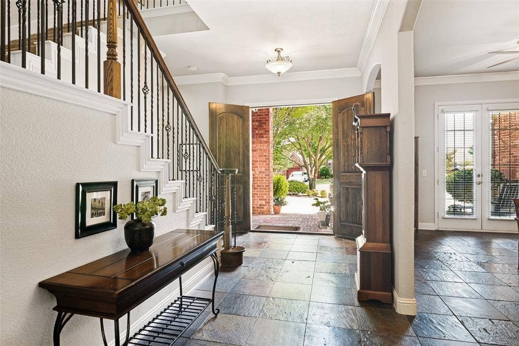 4305 Loch Haven Court, McKinney, TX 75072 Foyer featuring slate tile flooring, a staircase with wrought iron balusters and wood handrail, double front doors, and an arched entry