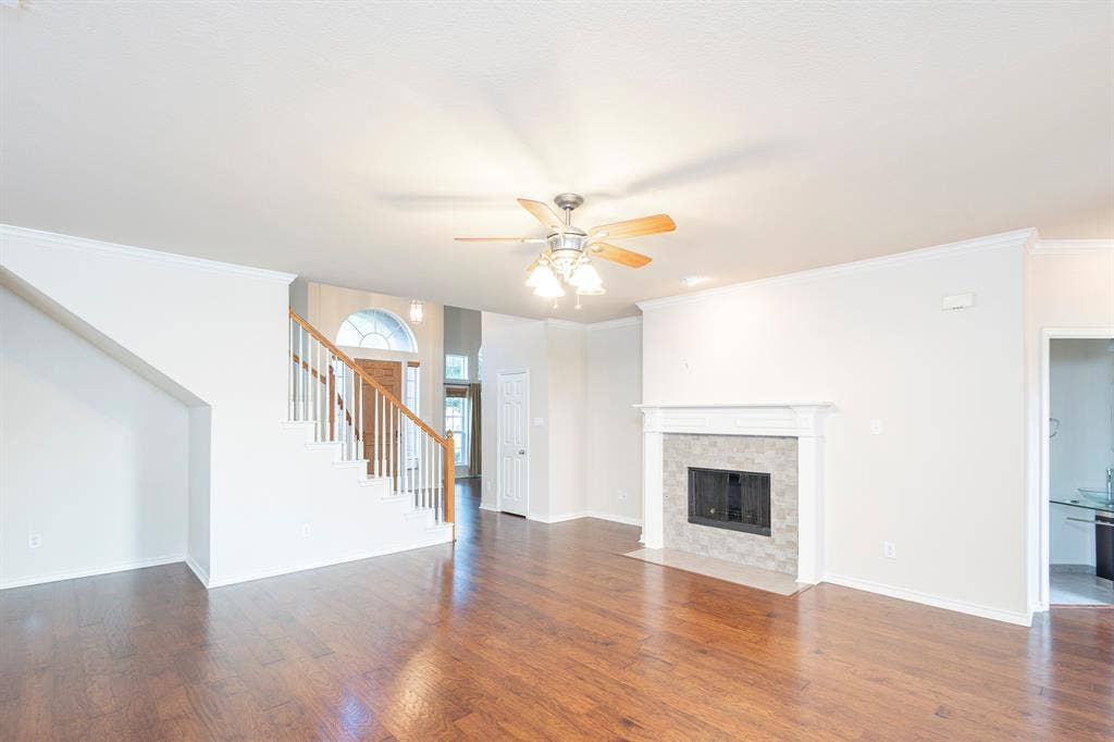 1200 Talley Lane, Frisco, TX 75033 Unfurnished living room featuring dark hardwood / wood-style floors, ceiling fan, a tiled fireplace, and crown molding