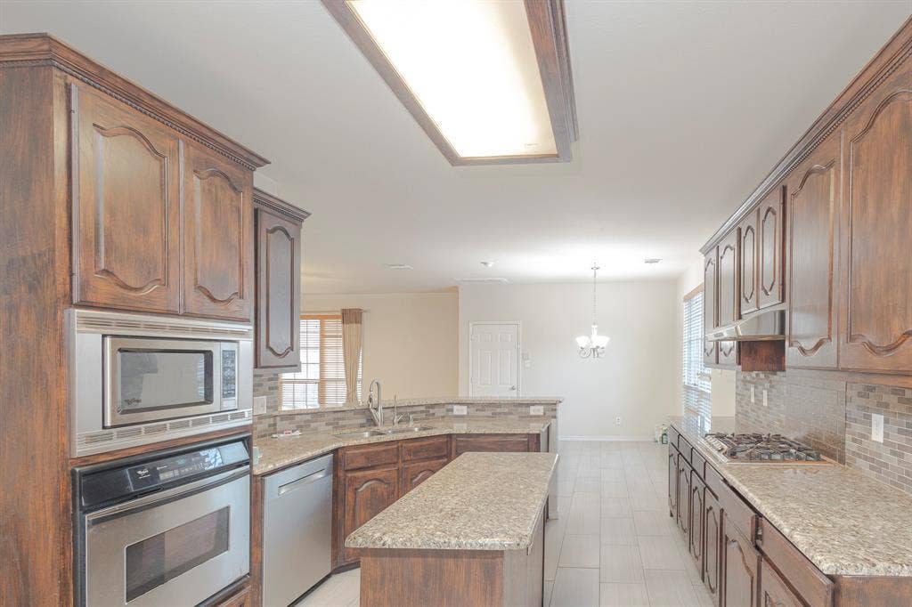 1200 Talley Lane, Frisco, TX 75033 Kitchen with a kitchen island, stainless steel appliances, light tile flooring, and backsplash