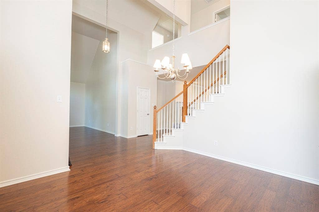 1200 Talley Lane, Frisco, TX 75033 Spare room with dark wood-type flooring, a towering ceiling, and an inviting chandelier