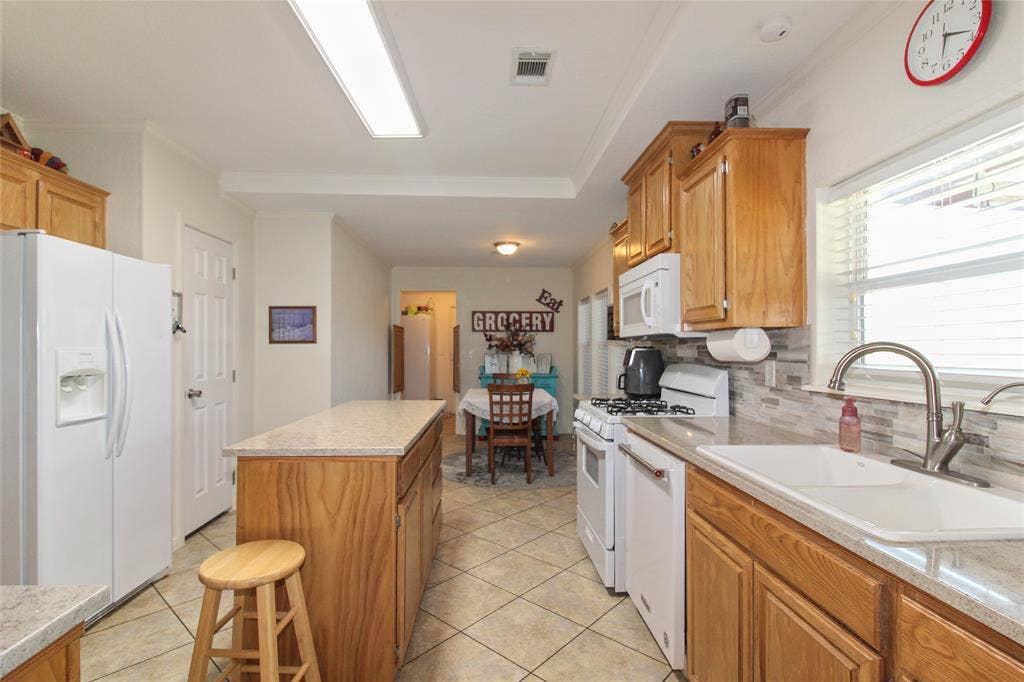 455 Hughes Cemetery Road, Italy, TX 76651 Kitchen featuring wood cabinetry, light-toned countertops, a tile backsplash, and a large sink with a gooseneck faucet