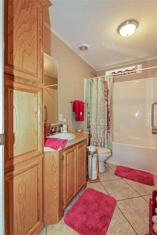 455 Hughes Cemetery Road, Italy, TX 76651 Bathroom featuring a built-in wood-finish cabinetry, a single vanity with an integrated sink, a commode, and a tub/shower combination