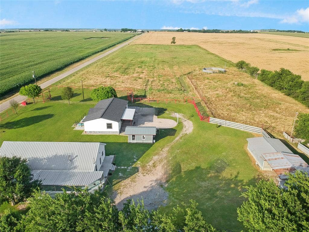 455 Hughes Cemetery Road, Italy, TX 76651 Expansive property featuring multiple structures, including a primary residence with a dark shingle roof and a separate metal-roofed building