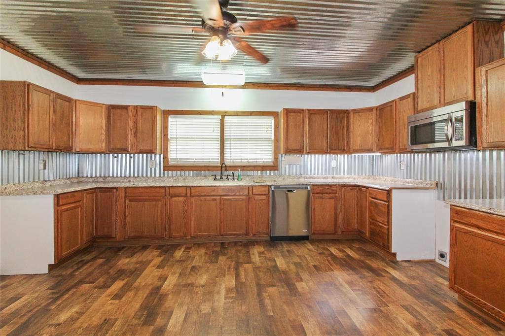 455 Hughes Cemetery Road, Italy, TX 76651 1936 HOUSE Kitchen featuring wood-finish flooring, extensive wood cabinetry, L-shaped countertops, stainless steel dishwasher, and a built-in microwave