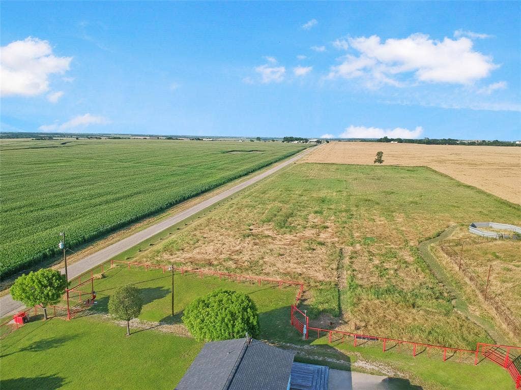 455 Hughes Cemetery Road, Italy, TX 76651 Expansive property featuring a paved road, fenced perimeter, and mature trees, surrounded by agricultural fields