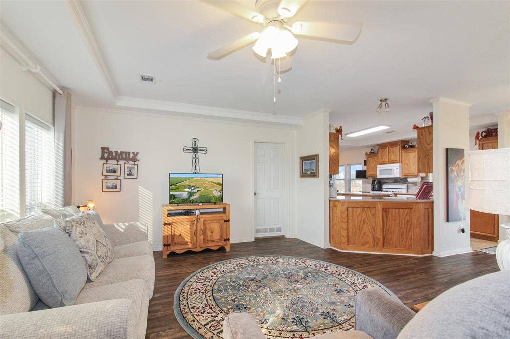 455 Hughes Cemetery Road, Italy, TX 76651 Spacious living area featuring wood-finish flooring, ample natural light from multiple windows, and a ceiling fan