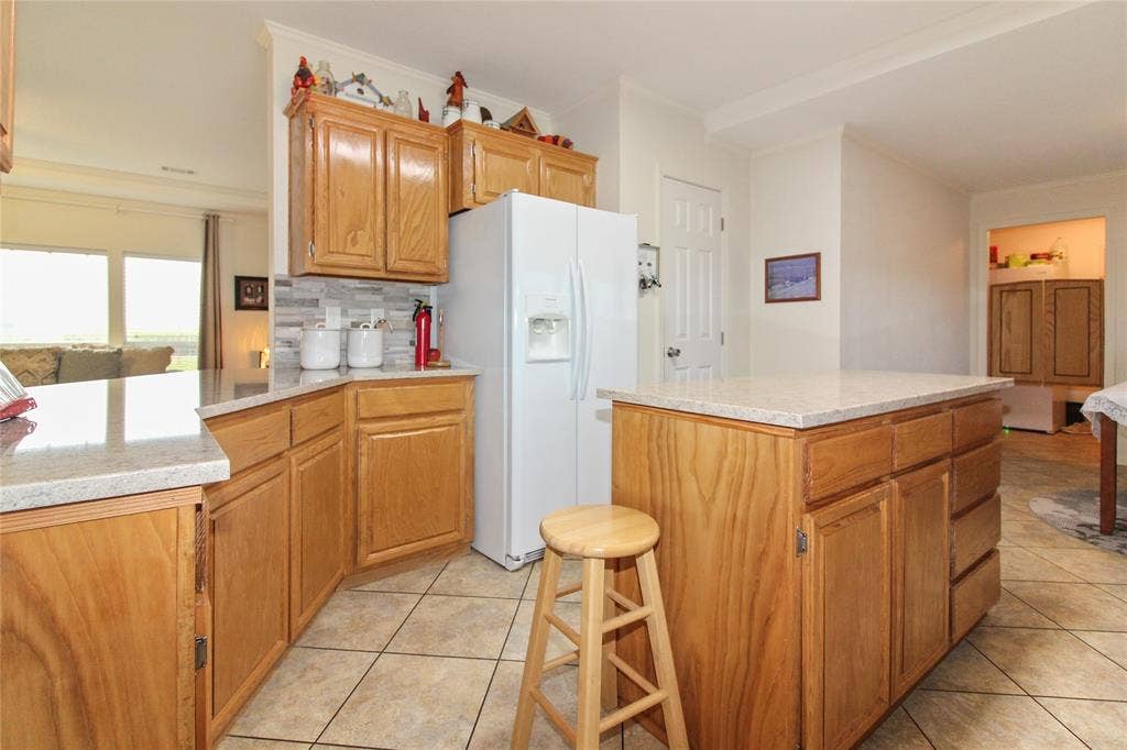 455 Hughes Cemetery Road, Italy, TX 76651 Kitchen featuring wood cabinetry, stone-look countertops, a tile backsplash, and tile flooring