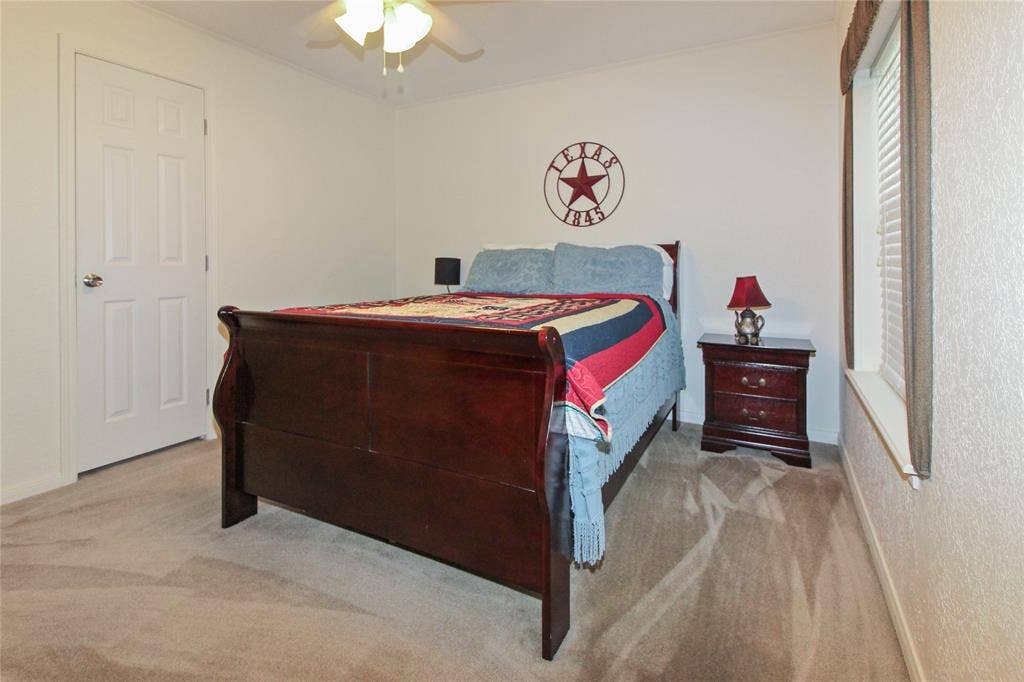 455 Hughes Cemetery Road, Italy, TX 76651 Carpeted bedroom featuring a ceiling fan, a white paneled door, and a window with blinds