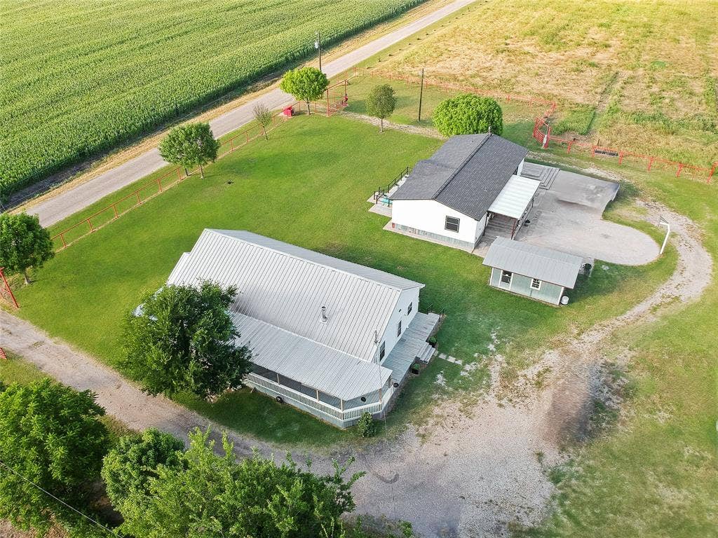455 Hughes Cemetery Road, Italy, TX 76651 Expansive property featuring two structures with pitched roofs, a smaller auxiliary building, and a gravel driveway