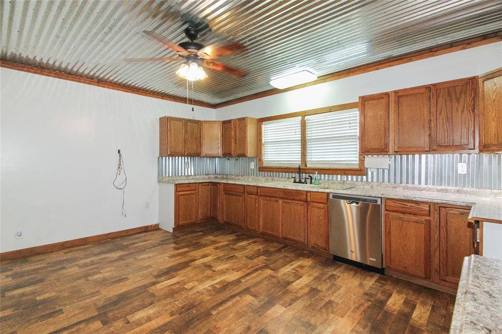 455 Hughes Cemetery Road, Italy, TX 76651 1936 HOUSE Kitchen featuring a corrugated metal ceiling, wood-finish flooring, wood cabinetry, stone-look countertops, and a stainless steel dishwasher