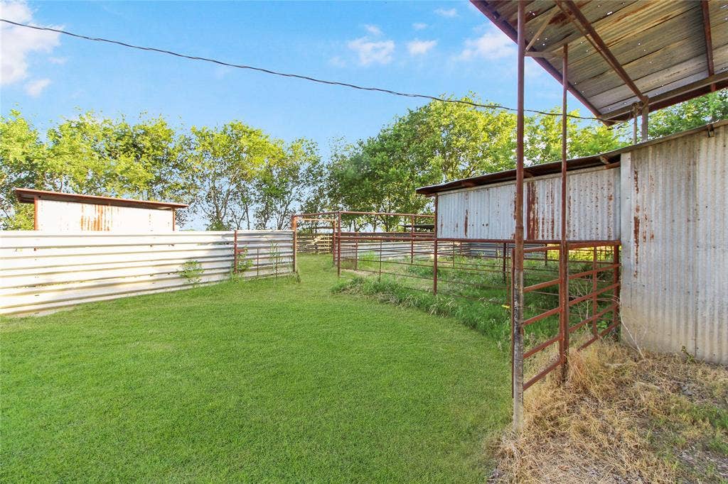 455 Hughes Cemetery Road, Italy, TX 76651 Outdoor fenced area featuring a grass lawn, corrugated metal fencing, and multiple metal corrals