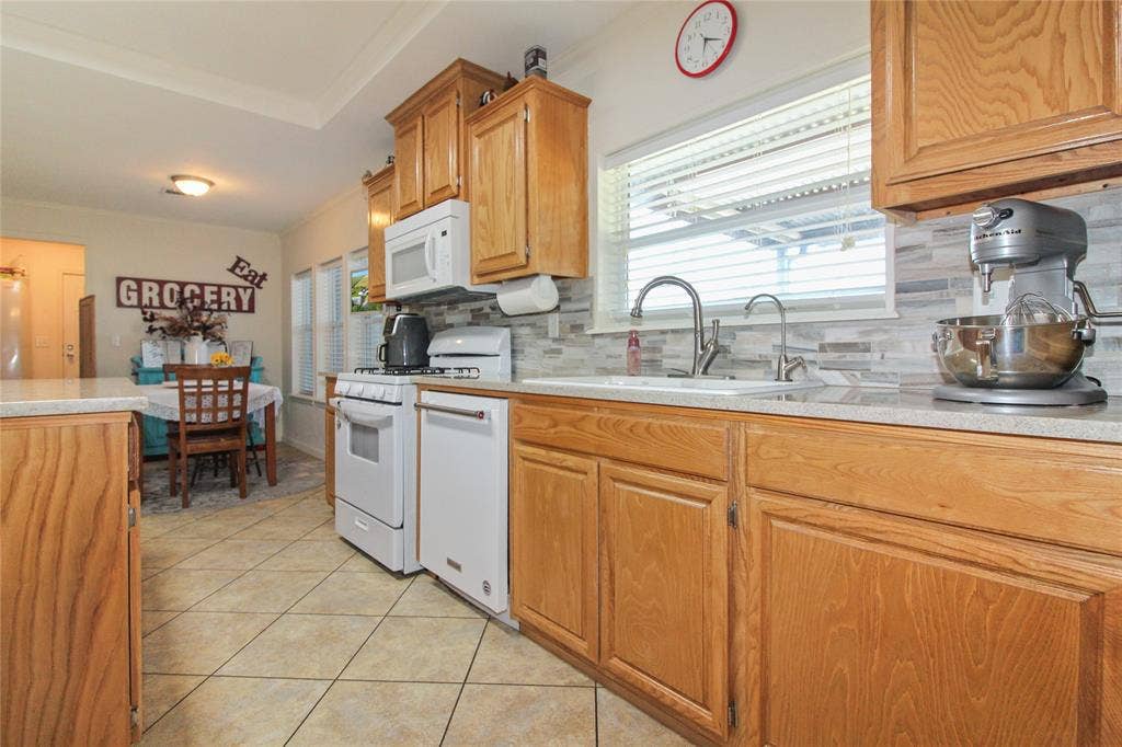 455 Hughes Cemetery Road, Italy, TX 76651 Kitchen featuring wood-finish cabinetry, light-toned countertops, and a full suite of white appliances