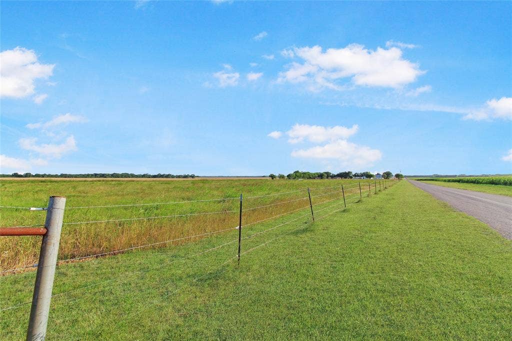 455 Hughes Cemetery Road, Italy, TX 76651 Expansive green fields alongside a paved road, bordered by a wire fence with metal posts