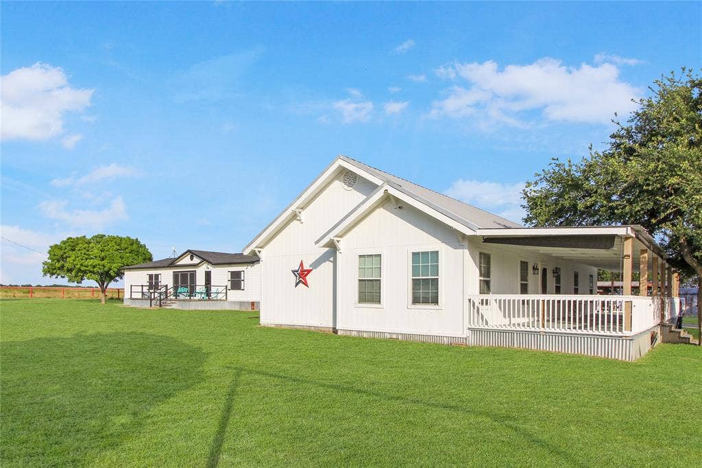 455 Hughes Cemetery Road, Italy, TX 76651 White-sided exterior with a metal roof and an expansive lawn