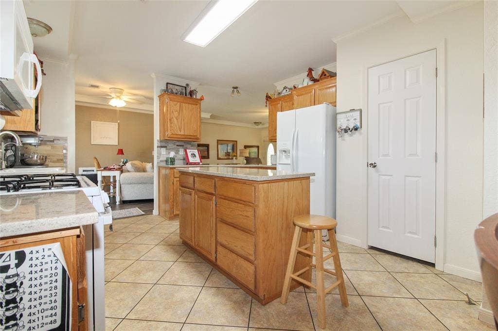 455 Hughes Cemetery Road, Italy, TX 76651 Kitchen featuring a central island with storage, light wood cabinetry, light-toned countertops, and tile flooring