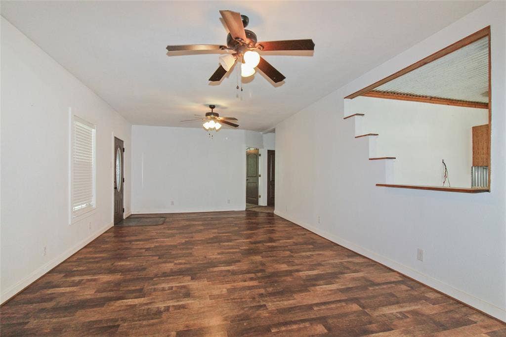 455 Hughes Cemetery Road, Italy, TX 76651 1936 HOUSE Spacious living area featuring wood-finish flooring, two ceiling fans with integrated lighting, and a white interior paint scheme