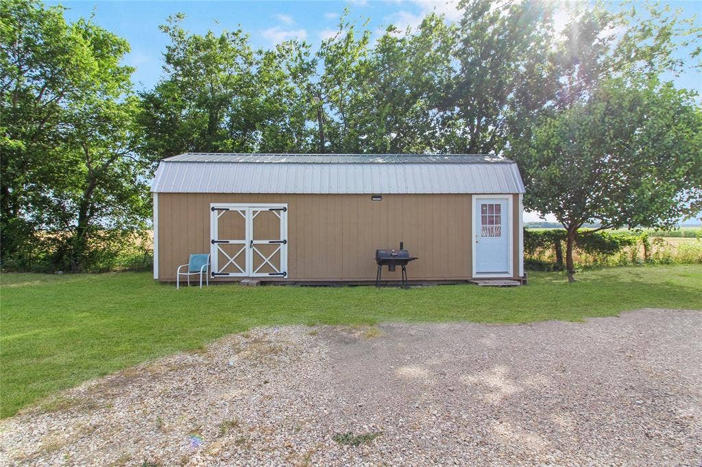 455 Hughes Cemetery Road, Italy, TX 76651 Freestanding outbuilding with a corrugated metal roof, tan siding, and white trim