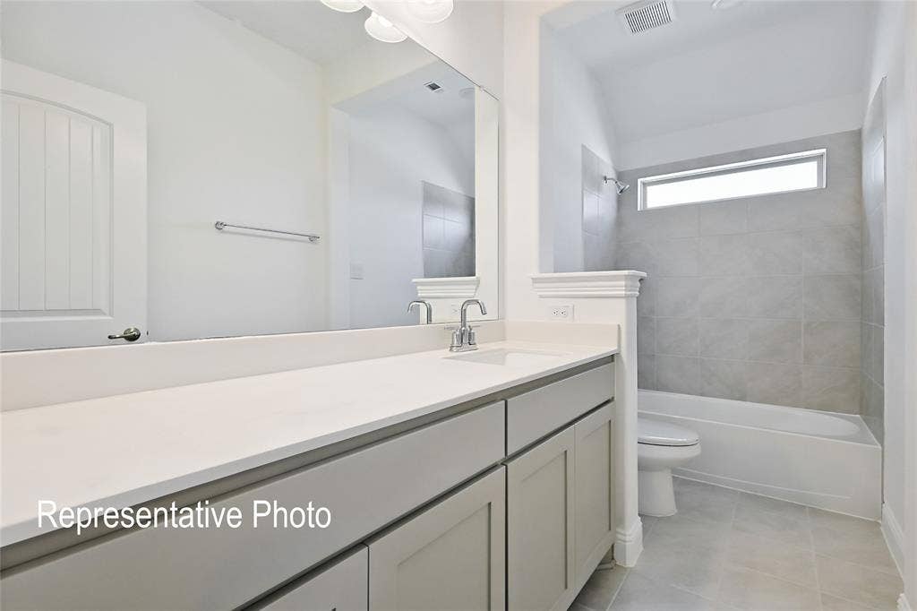 Bathroom featuring a spacious vanity with an undermount sink, a large mirror, contemporary cabinetry, and a full-size bathtub with a tiled surround
