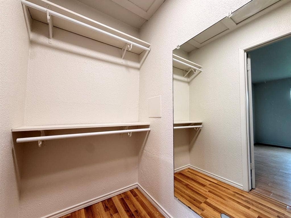 14003 Brookgreen Drive, Dallas, TX 75240 Walk-in closet featuring wood-finish flooring, two levels of shelving, two integrated hanging rods, and a full-length wall mirror