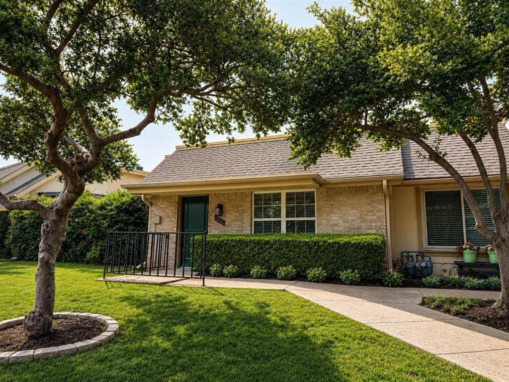 14003 Brookgreen Drive, Dallas, TX 75240 Brick and stucco exterior featuring a dark green entry door with an overhead light fixture