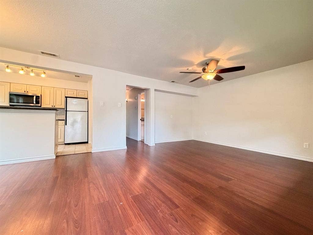 14003 Brookgreen Drive, Dallas, TX 75240 Spacious living area featuring wood-finish flooring, a ceiling fan, and an open concept layout with a kitchen pass-through