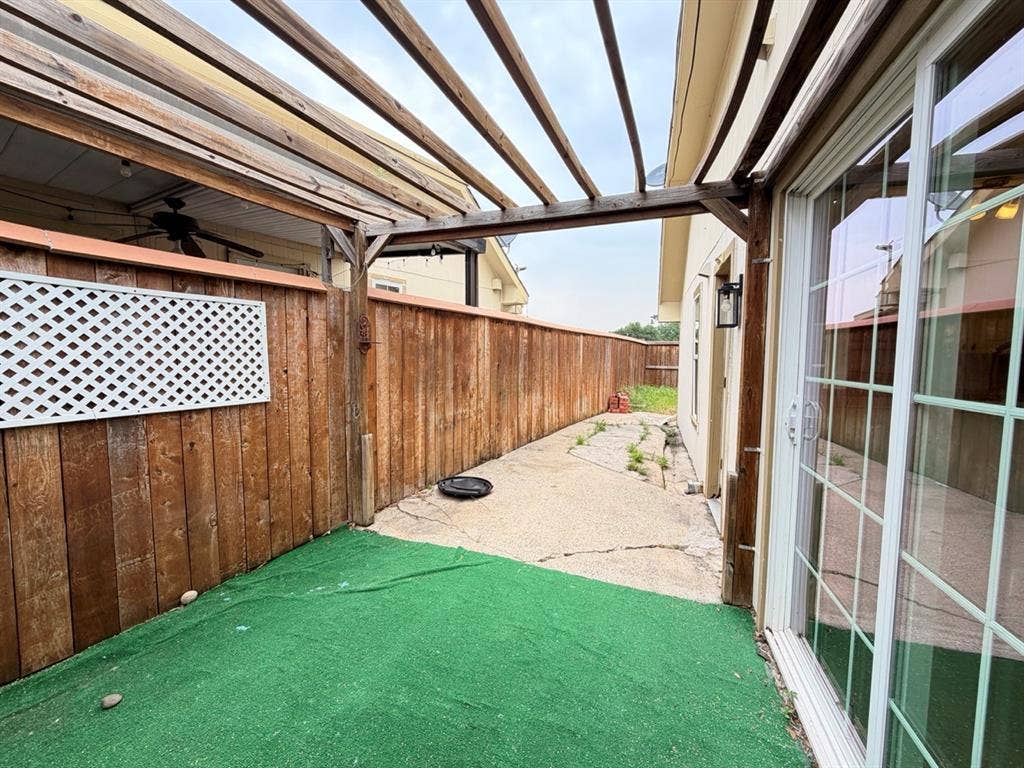 14003 Brookgreen Drive, Dallas, TX 75240 Patio area featuring a wood pergola structure, sliding glass door entry, full-height privacy fencing, and a combination of concrete and turf flooring