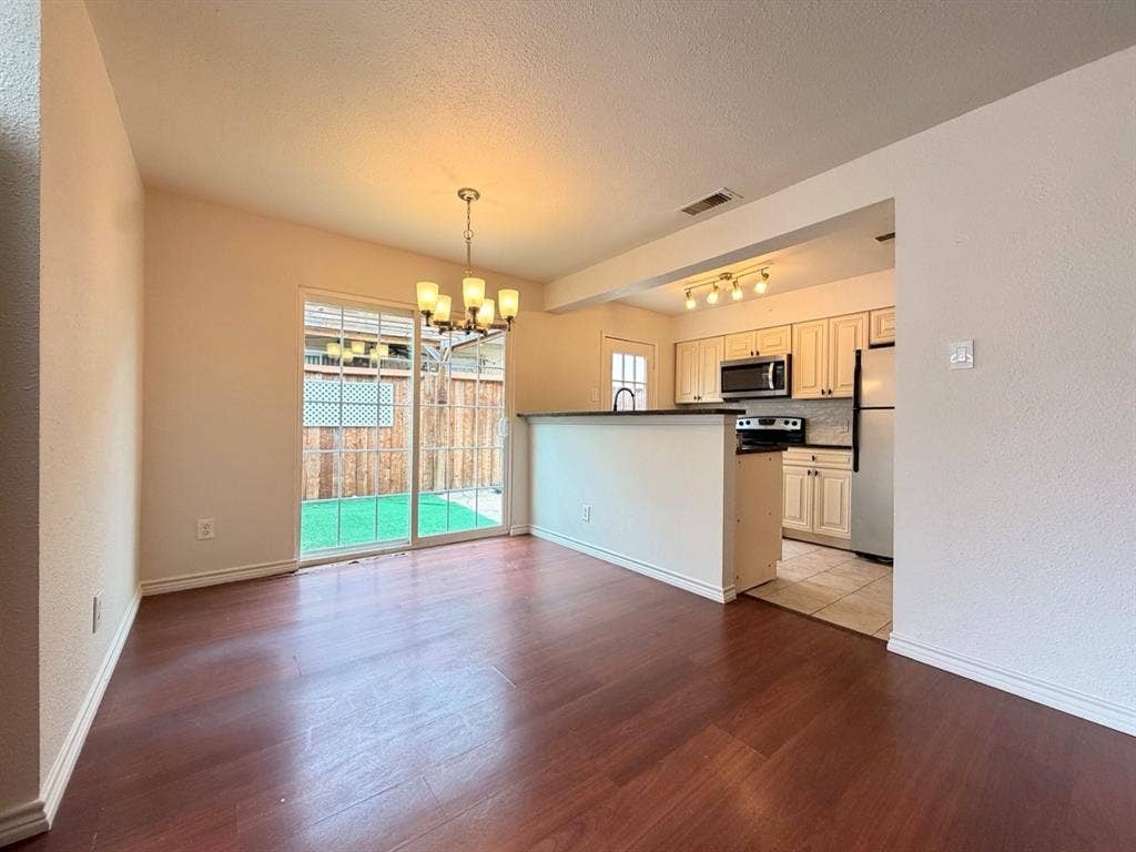 14003 Brookgreen Drive, Dallas, TX 75240 Open concept living area featuring dark wood-finish flooring, a contemporary chandelier, and a sliding glass door to a private outdoor space