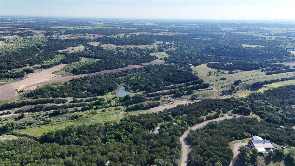 Expansive aerial showcasing a vast landscape of mature trees and open fields
