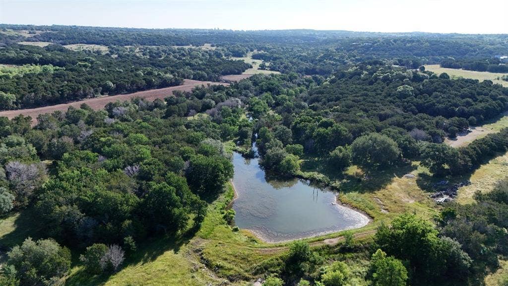 Natural water feature with surrounding wooded areas and open fields