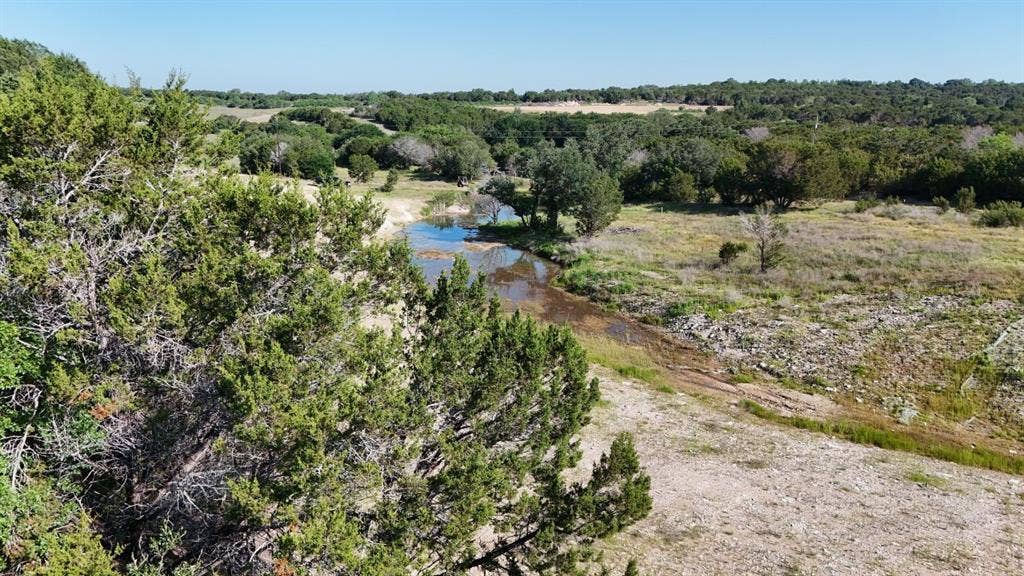 Expansive natural landscape featuring a winding waterway, mature trees, and varied terrain