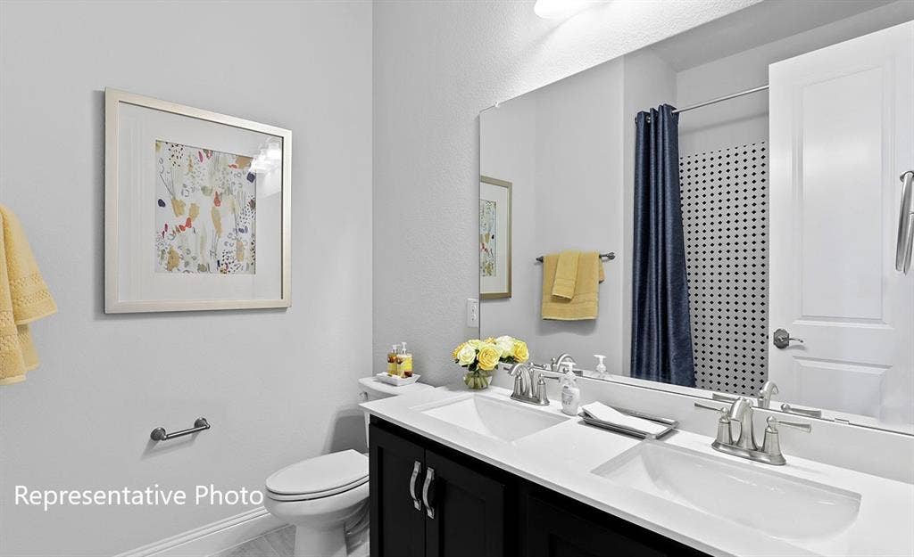 1140 Beaumont Lane, Red Oak, TX 75154 Bathroom vanity featuring dual under-mount sinks, a wide mirror, and dark cabinetry with brushed nickel hardware