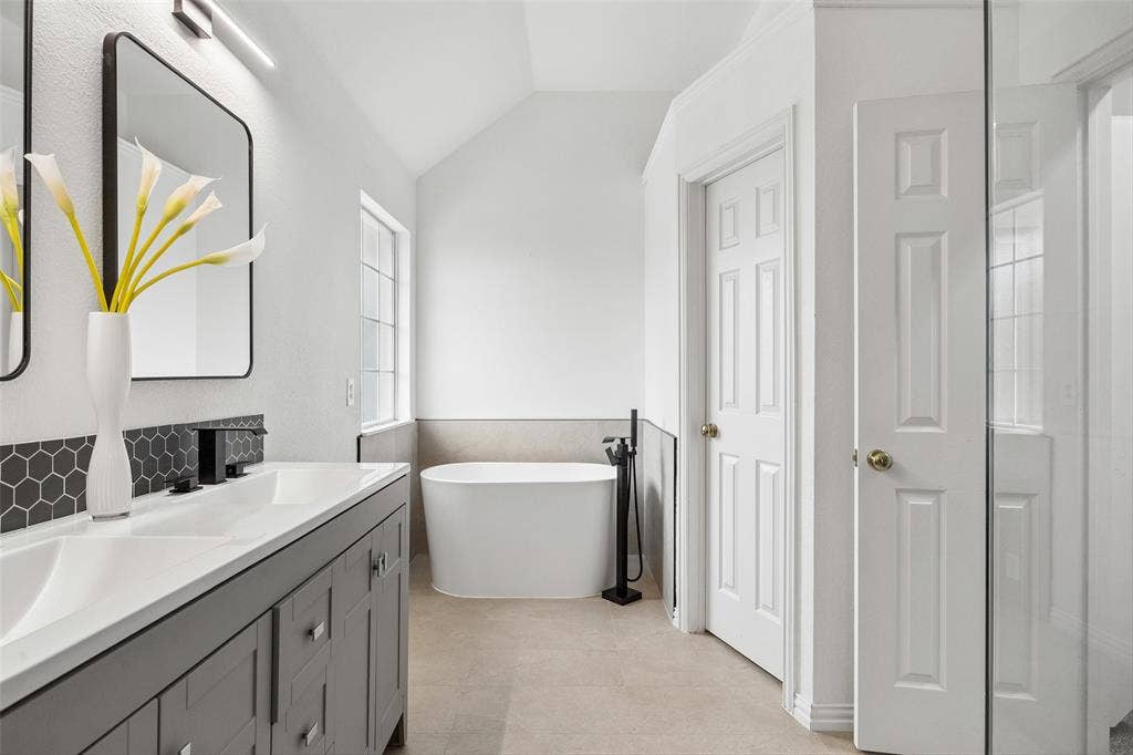 2701 Oates Drive, Plano, TX 75093 Dual vanity with white countertops, matte black faucets, and hexagonal tile backsplash