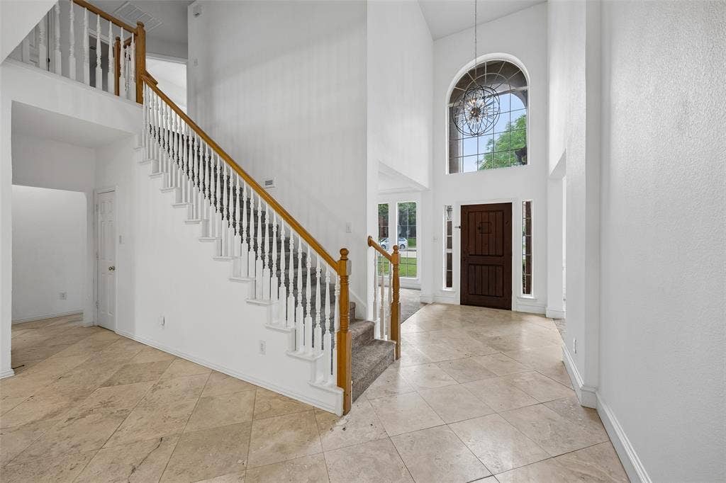 2701 Oates Drive, Plano, TX 75093 Two-story foyer featuring an arched window, a dark wood entry door with flanking sidelights, and a grand staircase with wood handrails