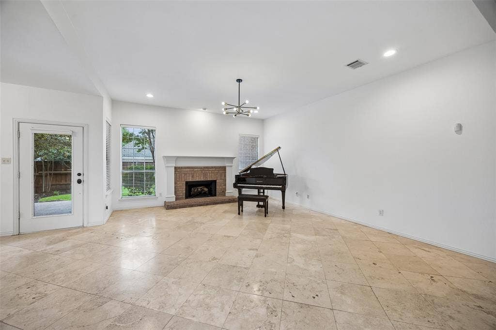 2701 Oates Drive, Plano, TX 75093 Spacious room featuring a brick fireplace with a white mantel, and a contemporary multi-arm chandelier