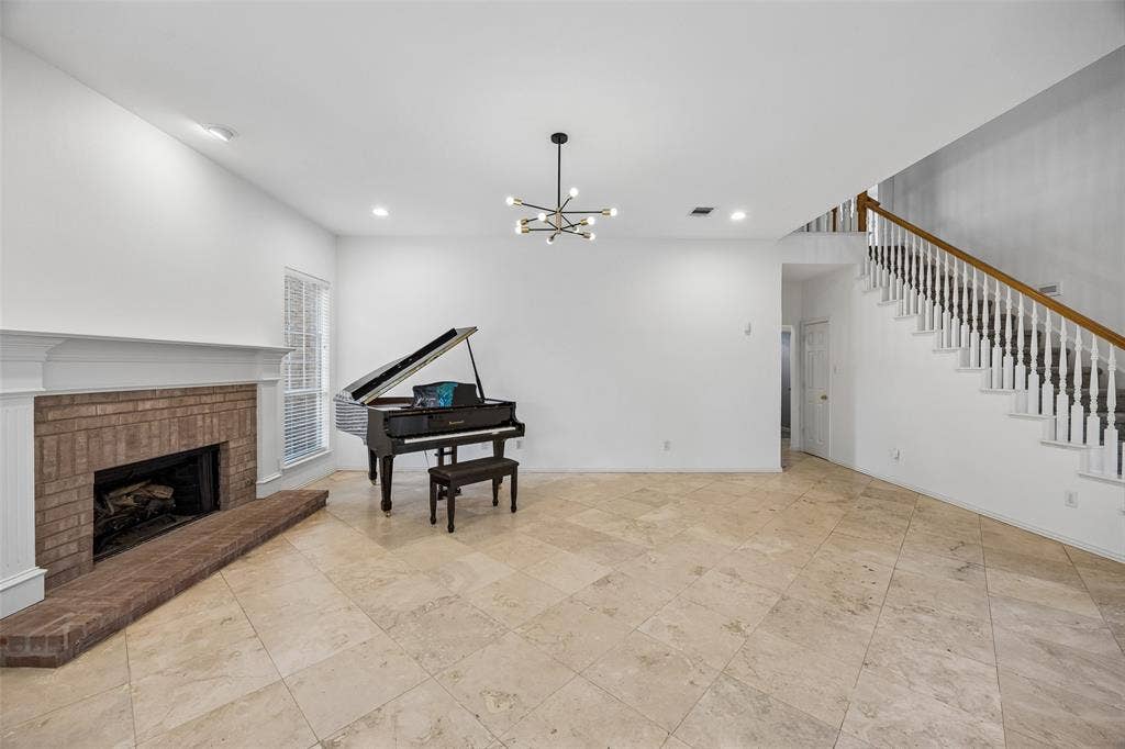 2701 Oates Drive, Plano, TX 75093 Spacious open-concept living area featuring a fireplace with a brick surround, white mantle, multiple windows, and a built-in breakfast bar with a dark countertop