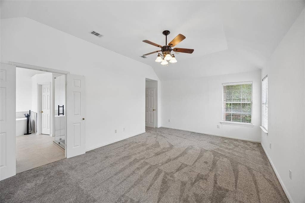 2701 Oates Drive, Plano, TX 75093 Spacious carpeted room featuring a ceiling fan with integrated lighting, vaulted ceilings, and white painted walls