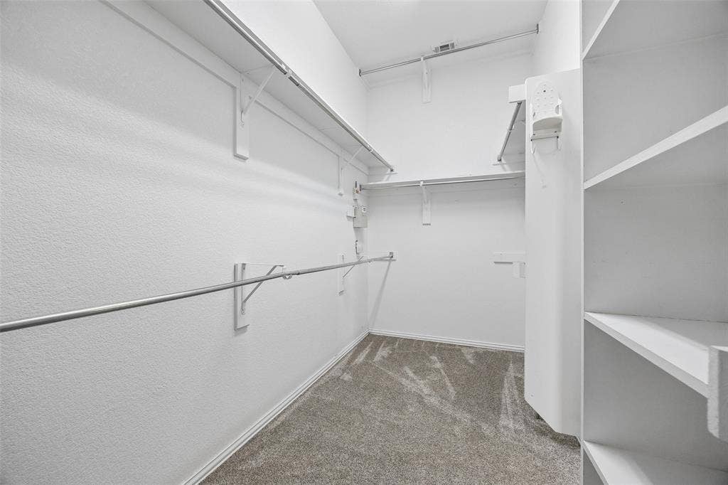 2701 Oates Drive, Plano, TX 75093 Walk-in closet featuring built-in shelving, multiple hanging rods, and neutral-toned carpeting