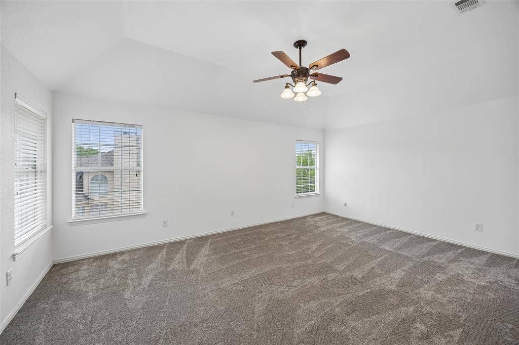 2701 Oates Drive, Plano, TX 75093 Spacious room featuring vaulted ceilings, neutral-toned carpet, multiple windows, a ceiling fan with integrated lighting, and neutral white walls
