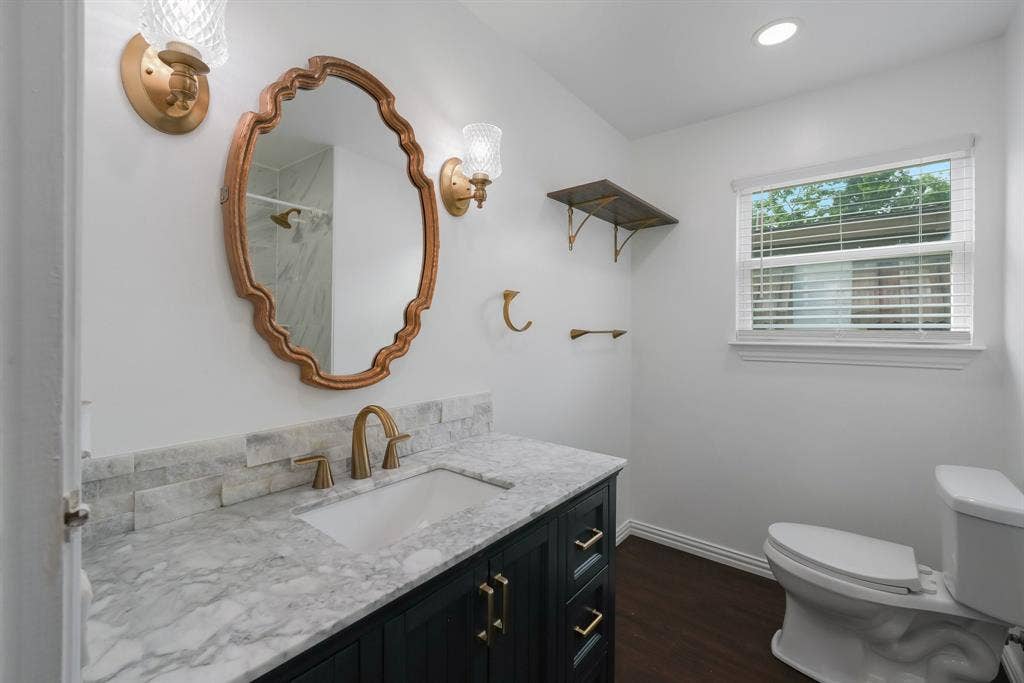 414 Avenue I, Dallas, TX 75203 Bathroom featuring a vanity with a light-toned countertop, a decorative mirror, and wall-mounted sconces.