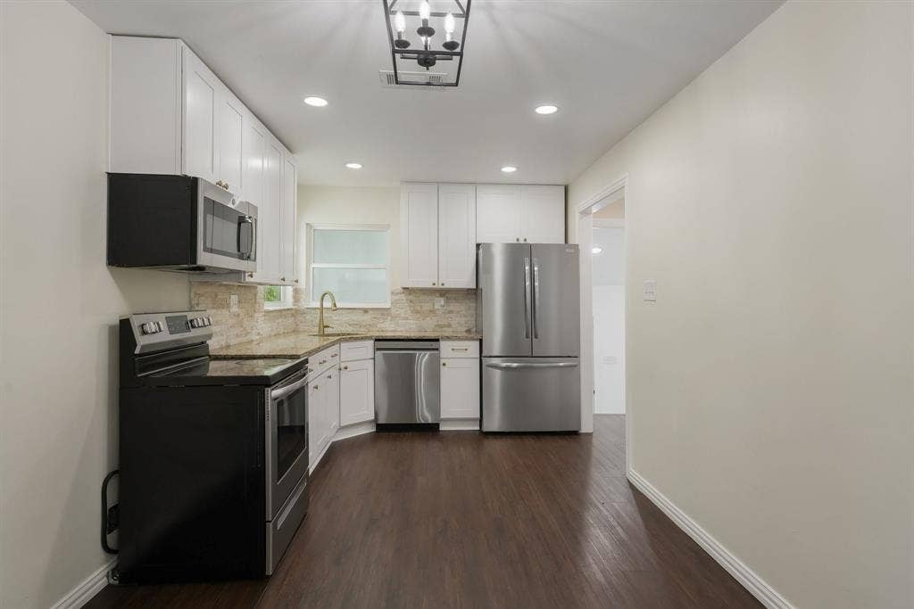 414 Avenue I, Dallas, TX 75203 Modern kitchen featuring white cabinetry, stainless steel appliances, granite countertops, gold fixtures.