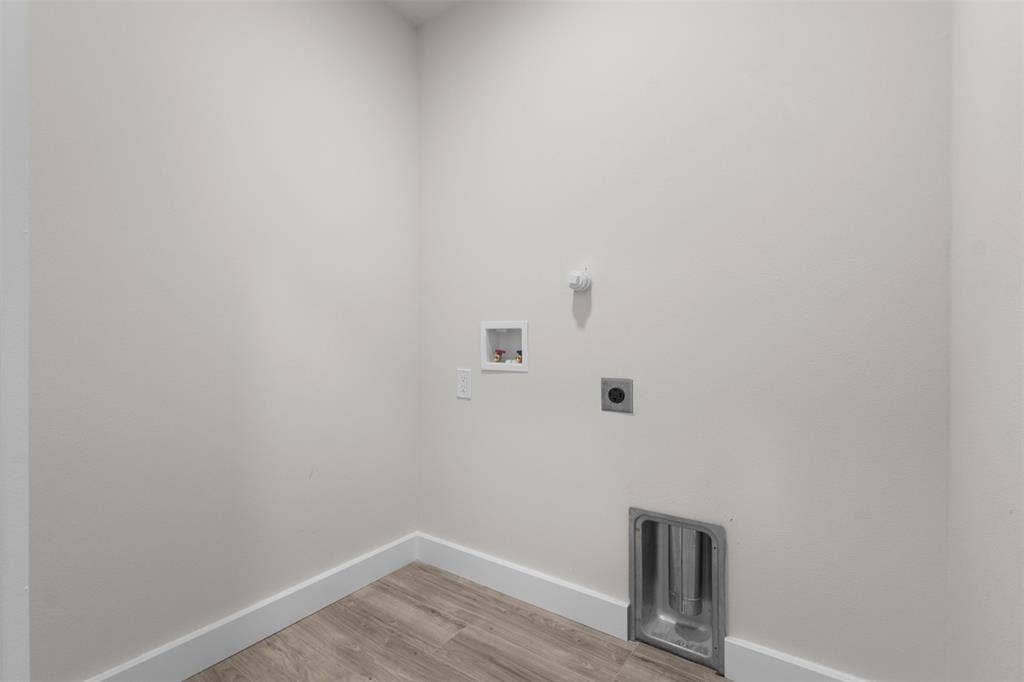 1507 E Waco Avenue, Dallas, TX 75216 Dedicated utility space featuring light-toned walls, wood-finish flooring, and crisp white baseboards