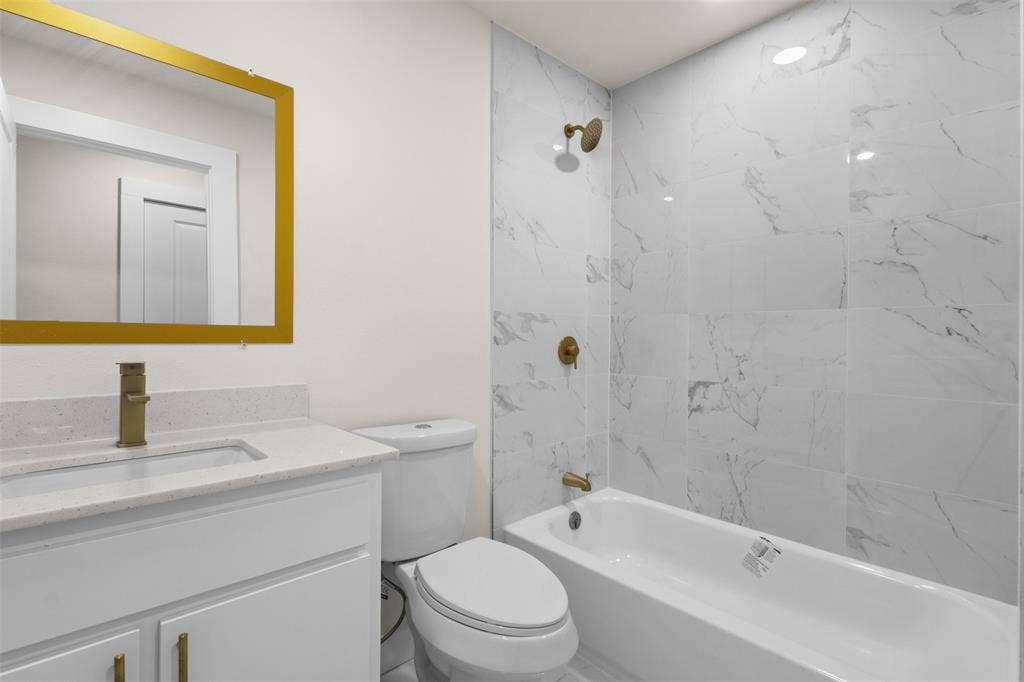 1507 E Waco Avenue, Dallas, TX 75216 Bathroom featuring a vanity with an integrated sink, a gold-framed mirror, and a toilet