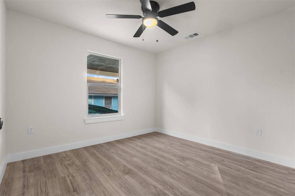 1507 E Waco Avenue, Dallas, TX 75216 Bright room featuring wood-finish flooring, white baseboards, a single window with white trim, and a ceiling fan with integrated lighting